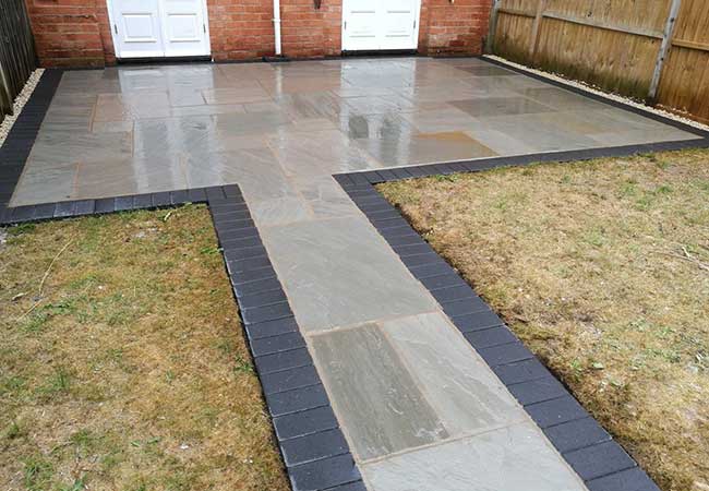 A rear patio we created in Radcliffe on Trent (Nottinghamshire) using a charcoal pavior border with a kandla grey indian sandstone. We also turfed the grassed area.