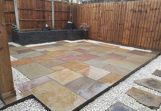 A full rear landscape including fencing, brick planter, multi buff indian sandstone and stone chippings to create this patio in Awsworth, Nottingham.